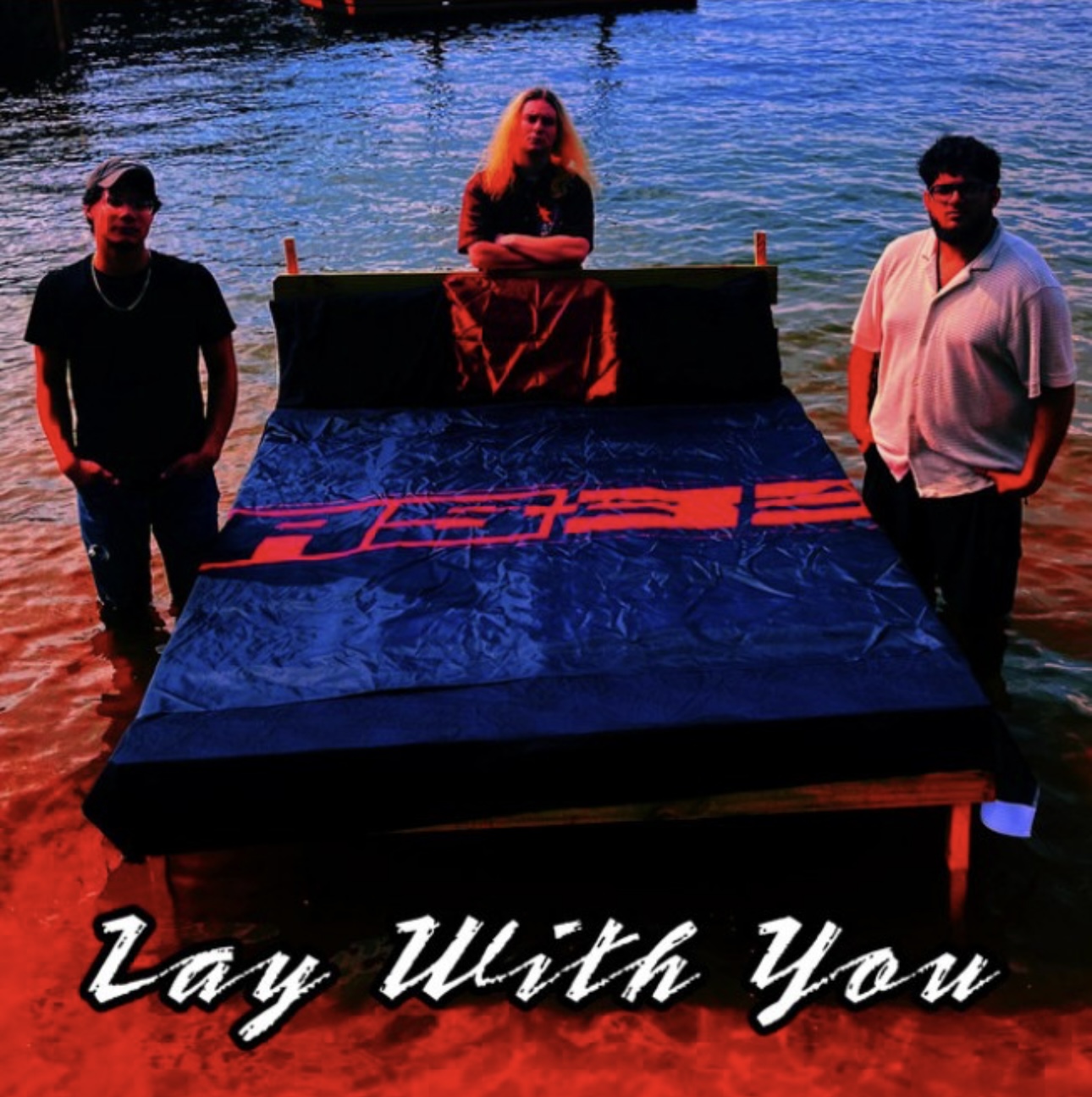 AS-33 single cover for Lay With You: the three band members standing in shallow water around a bed frame, bathed in red and blue light
