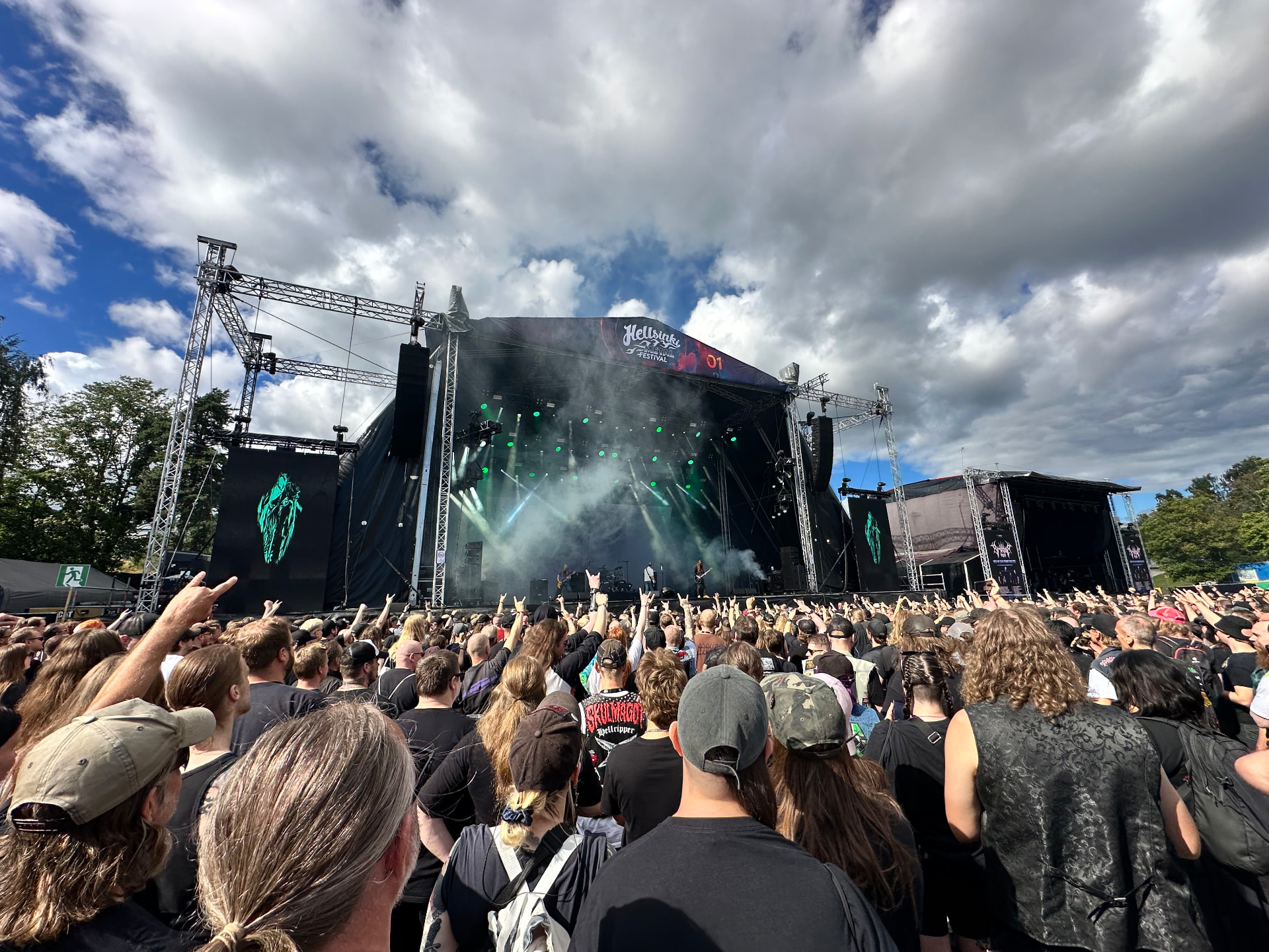 Carcass — precision brutality under a Helsinki sky. Carcass performing at Hellsinki Metal Festival 2026 under green lights with horns raised across the crowd