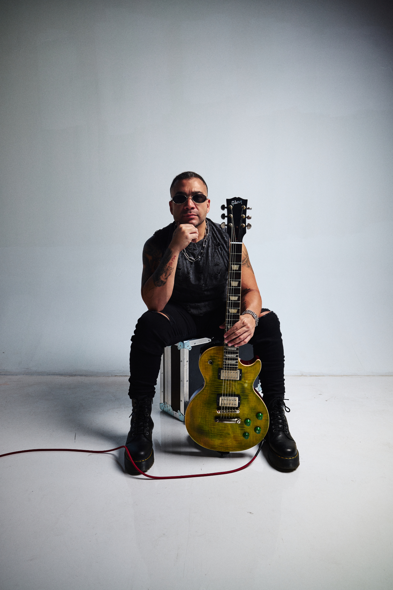 Max Padron — recording artist, session and touring guitarist, producer. Max Padron seated on a flight case holding a Gibson Les Paul with a green finish