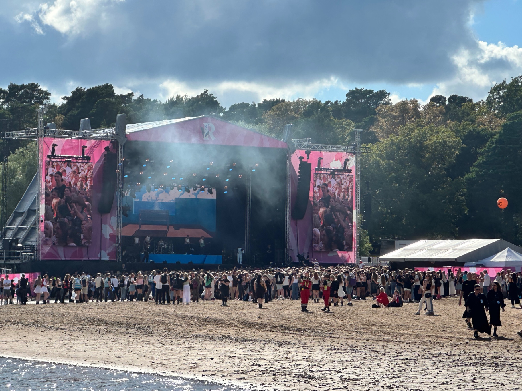 View from Ruisrock — main stage, sand, crowd, sea. Ruisrock 2026 main stage on the beach at Ruissalo with crowd and pine trees