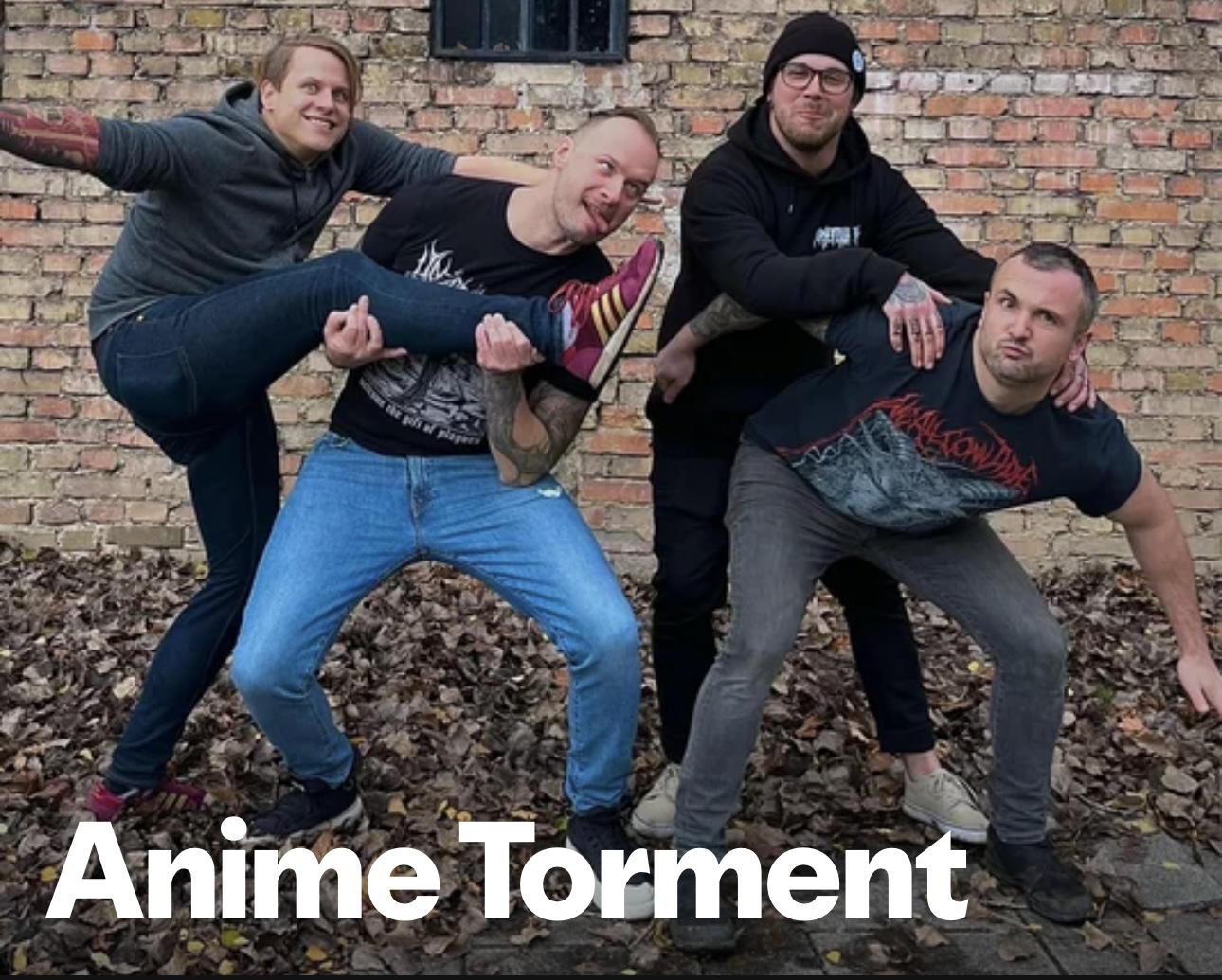 Anime Torment band photo — four members posing against a brick wall on autumn leaves